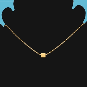 Detail of a minimalist gold geometric square pendant on a delicate box chain necklace
