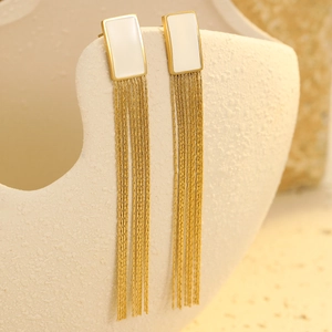 Detail of gold tassel earrings with white rectangular stone on a ceramic holder
