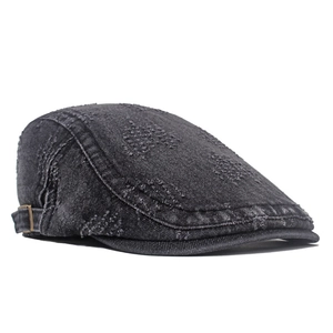 Macro shot of distressed denim newsboy hat showing faded texture and bronze metal buckle