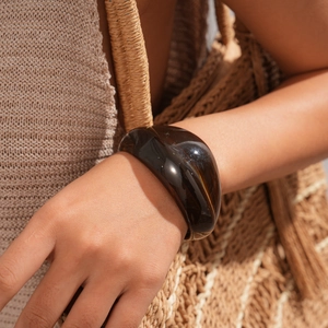 Close-up of wide amber acrylic bangle with tortoiseshell texture on a model's wrist