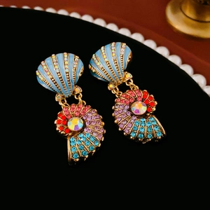Detailed close-up of shell and conch earrings with colorful crystals on velvet