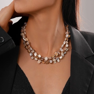 Macro detail of double-layer shell bead necklace featuring irregular brown and beige stones