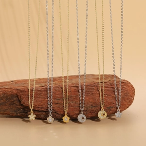 Detailed set of gold and silver flower necklaces with zircon pendants on wood background
