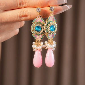 Détail de boucles d'oreilles dorées vintage avec pierre bleue et perles roses