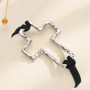 Close-up of a silver hollow cross bracelet with a black suede cord on a display stand