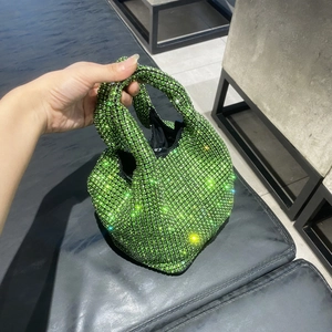 Detail of green rhinestone bucket bag featuring a unique knot handle and sparkling crystals