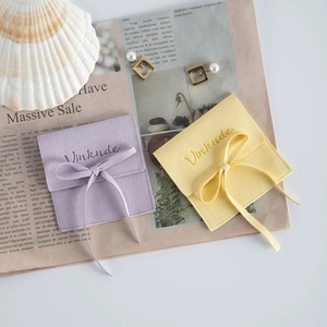 Detail of square microfiber jewelry pouches in purple and yellow with ribbon bows