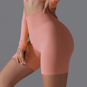 Detailed texture of seamless high-waist yoga shorts in vibrant coral pink knitted fabric