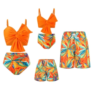 Tropical leaf print family swimwear set with orange halter tops and palm leaf bottoms