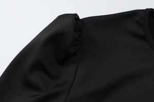 Vue détaillée des manches bouffantes structurées et de l'épaule plissée sur une robe noire