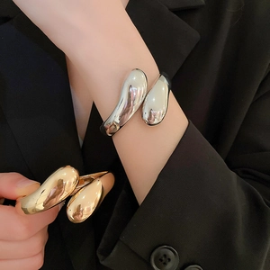 Dettaglio di bracciali aperti regolabili minimalisti nelle finiture oro e argento