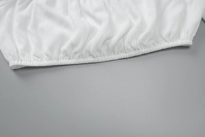Dettaglio del tessuto bianco strutturato con orlo elastico sul set crop top da spiaggia