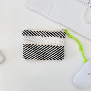 Detail view of woven black and white striped cosmetic bag with a neon green zipper puller
