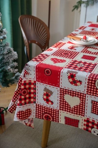 Detail of red plaid Christmas tablecloth with festive tree and stocking patterns