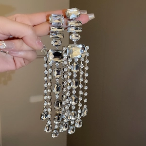 Detailed macro view of long silver tassels and geometric crystals on statement earrings