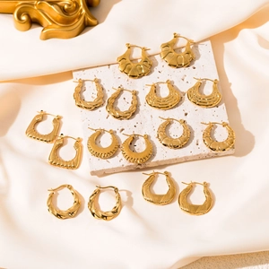 Elegant gold stainless steel hoop earrings with textured geometric patterns on silk fabric