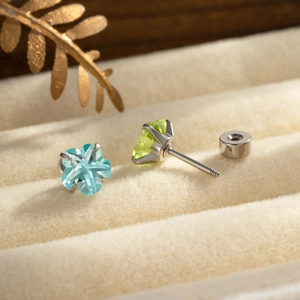 Boucles d'oreilles fleur argentée avec cristaux bleus et verts sur un support bijoux
