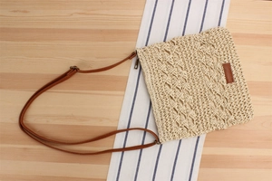 Detail of hand-woven straw crossbody bag with natural fiber texture and leather strap