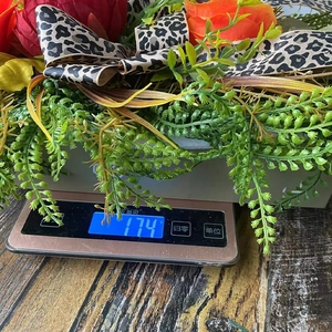 Detail view of autumn wreath showing 174g weight on scale with leopard bow and flowers
