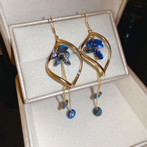 Dettaglio orecchini a foglia d'oro ritorta con cristalli blu e lunghe frange eleganti
