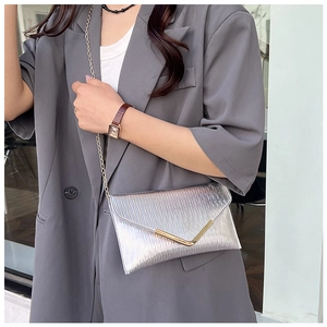 Détail du sac argenté plissé avec boucle en V dorée et texture verticale élégante
