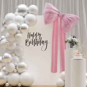 Pink ribbon decoration on white arch backdrop with balloons for birthday party setup
