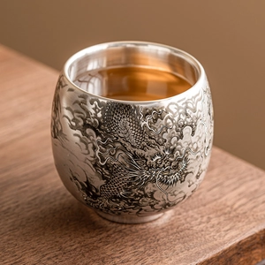 Tasse à thé argentée avec relief de dragon complexe remplie de thé infusé