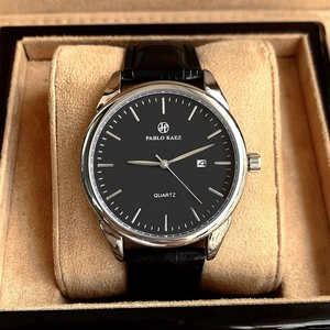 Macro detail of quartz watch featuring black dial, silver case, and calendar display