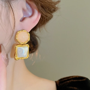 Close-up of retro geometric earrings with pink resin circles and square pearls on model
