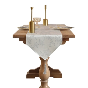 Elegant Christmas table runner with silver floral jacquard and tassels on wooden table