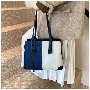 Detail shot of color-block denim and white canvas tote bag with dark blue leather straps