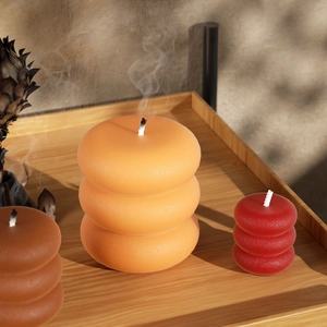 Three-tier bubble stacked scented candles in warm tones on a wooden tray with smoke