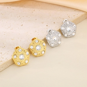 Detailed view of gold and silver irregular hammered stud earrings with clear zircon stones