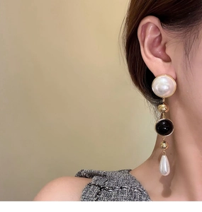 Detailed view of long 18k gold plated earrings with pearls and black beads on model