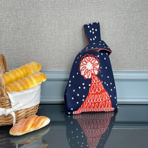 Détail du sac à main en tricot bleu marine avec motifs floraux rouges et coton épais