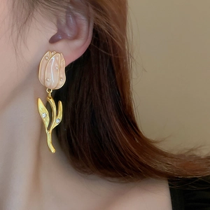Gros plan de boucles d'oreilles tulipe avec perles et cristaux portées par un modèle