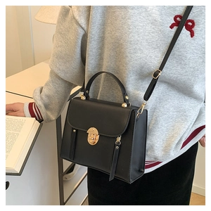 Détail d'un sac bandoulière minimaliste en cuir noir mat avec boucle en métal et longue sangle