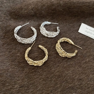 Detail view of woven twisted rope hoop earrings in polished gold and silver finishes