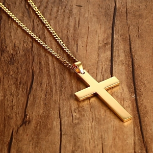 Polished gold stainless steel cross necklace for men on a dark wood background