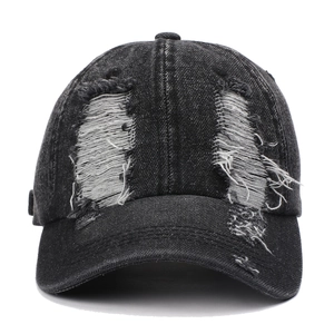 Detailed view of distressed holes and washed texture on a charcoal denim baseball cap