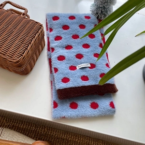 Detail of soft plush scarf with blue and red polka dots on white surface