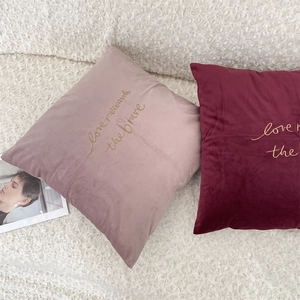 Detailed close-up of embroidered velvet pillow covers in mauve and burgundy colors