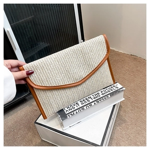 Detailed view of cream straw envelope clutch with brown leather trim and woven texture