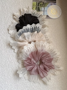 Detailed close-up of lace-edged scrunchies in black, beige, and dusty pink silk fabrics