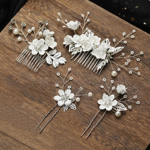 Detail of bridal hair comb set with white ceramic flowers and pearls on wooden surface
