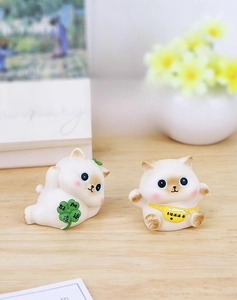 Close-up of cute resin cat figurines with clover and good luck messages on desktop