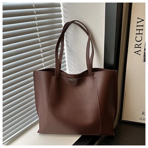 Close-up of large brown PU leather tote bag with stylish metal buckle and textured finish
