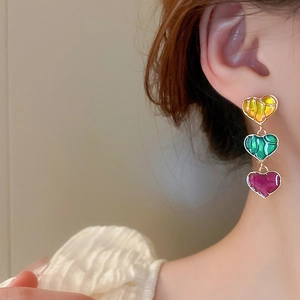Detail of colorful triple heart drop earrings with yellow, green and purple enamel finish