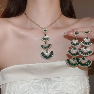 Detailed view of luxury gold fan-shaped necklace and earrings set on a model