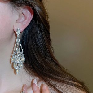 Dettaglio di orecchini a pendente in argento con cristalli indossati da una modella